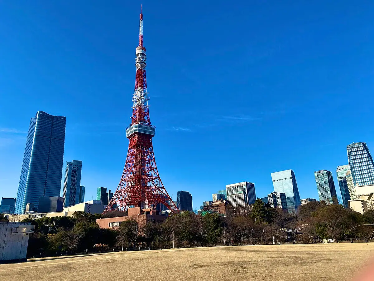 Tokyo Tower di sebalik padang rumput Shiba Park dengan langit biru