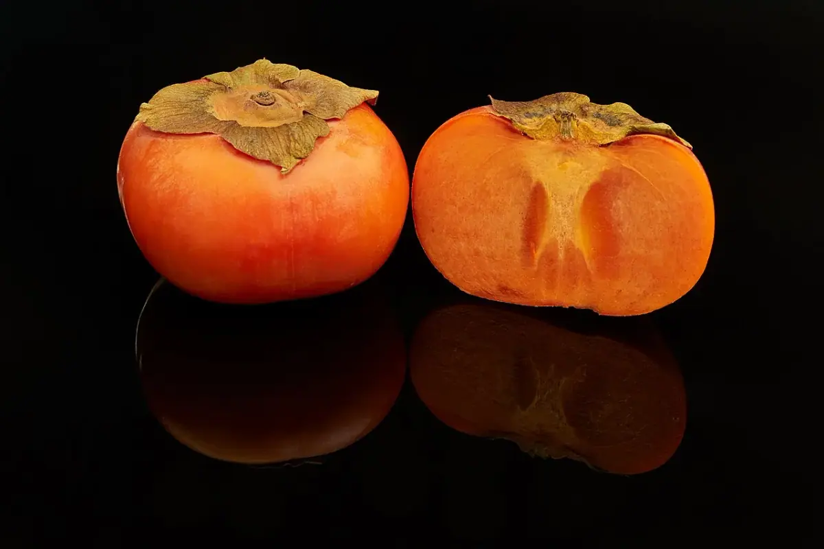 Des kakis orange, dont un coupé en deux
